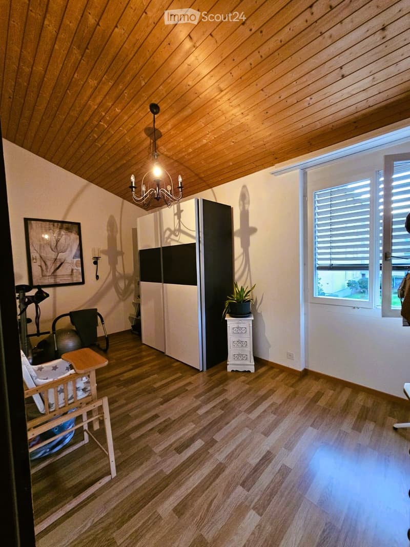 wooden floor, wooden ceiling, white walls, chandelier, sliding wardrobe, potted plant, picture frame, exercise equipment, wooden chair, wooden table