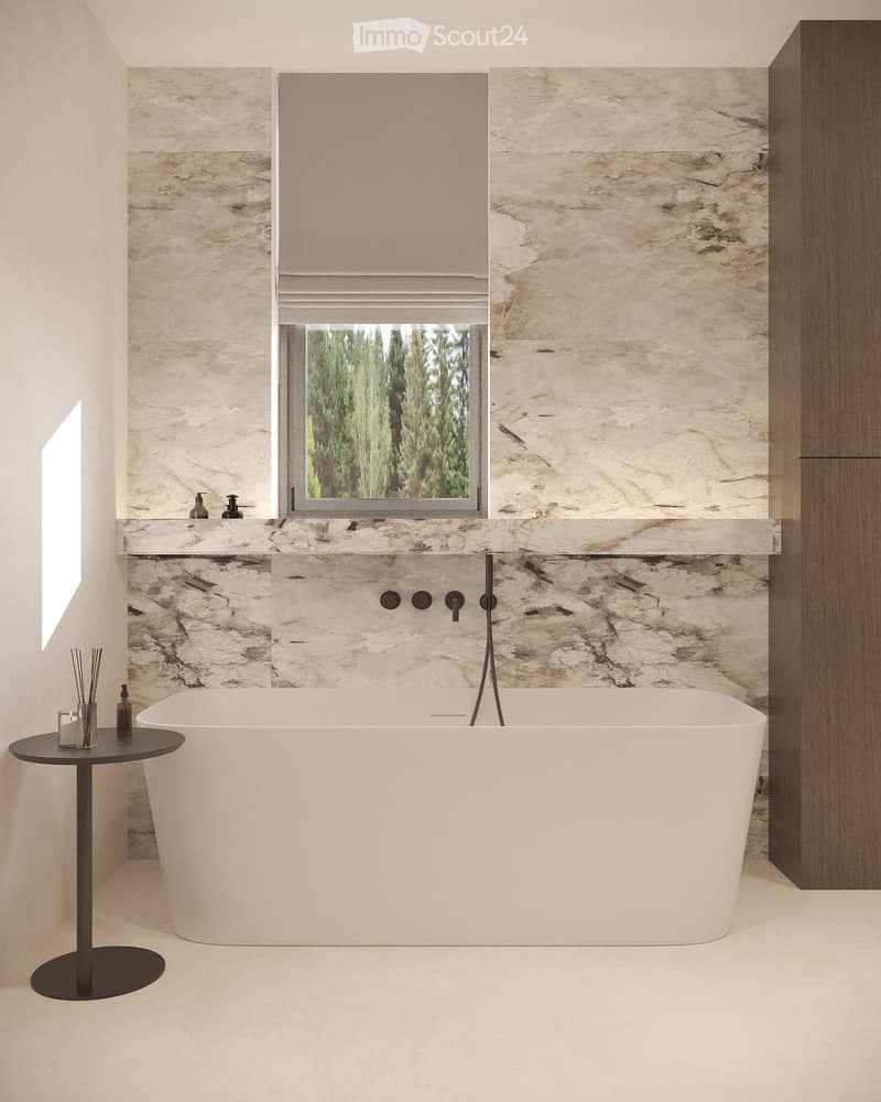 Bathroom with marble walls, white bathtub, black faucet, small table with glass and bottles, wooden cabinet, window with trees view