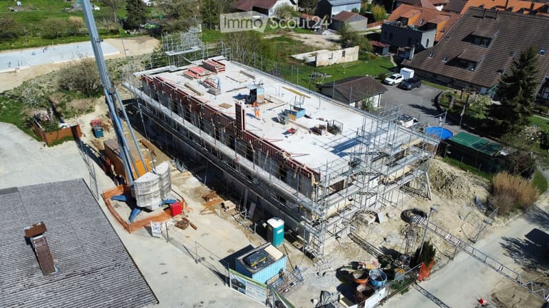 Building under construction, multiple floors, scaffolding, construction materials, vehicles parked
