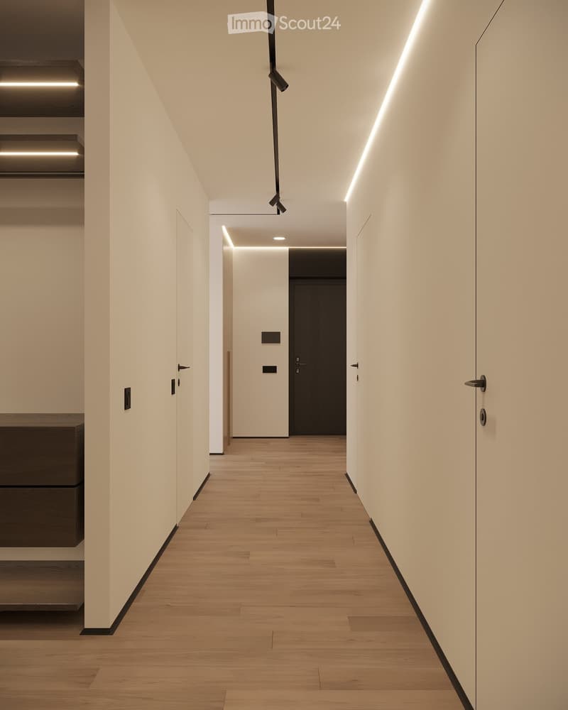 Modern hallway with light wooden flooring, white walls, and recessed lighting. Features sleek black door handles and a dark-toned door at the end.