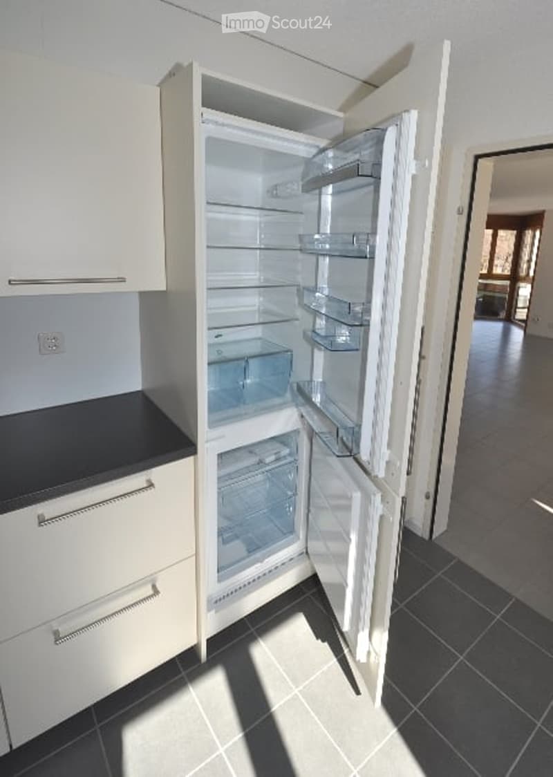 Open refrigerator, dishwasher, white kitchen cabinets, black countertop, power outlet, tiled floor