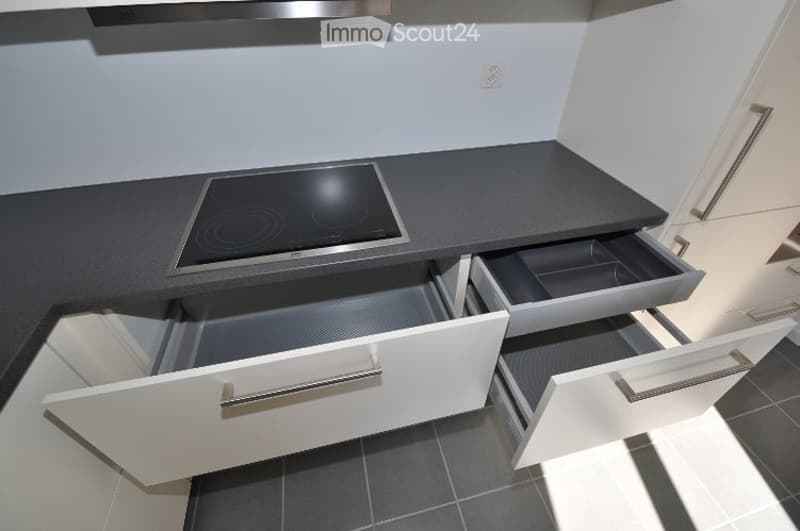 modern kitchen with grey countertop, electric stove, white cabinets, drawers, modern design