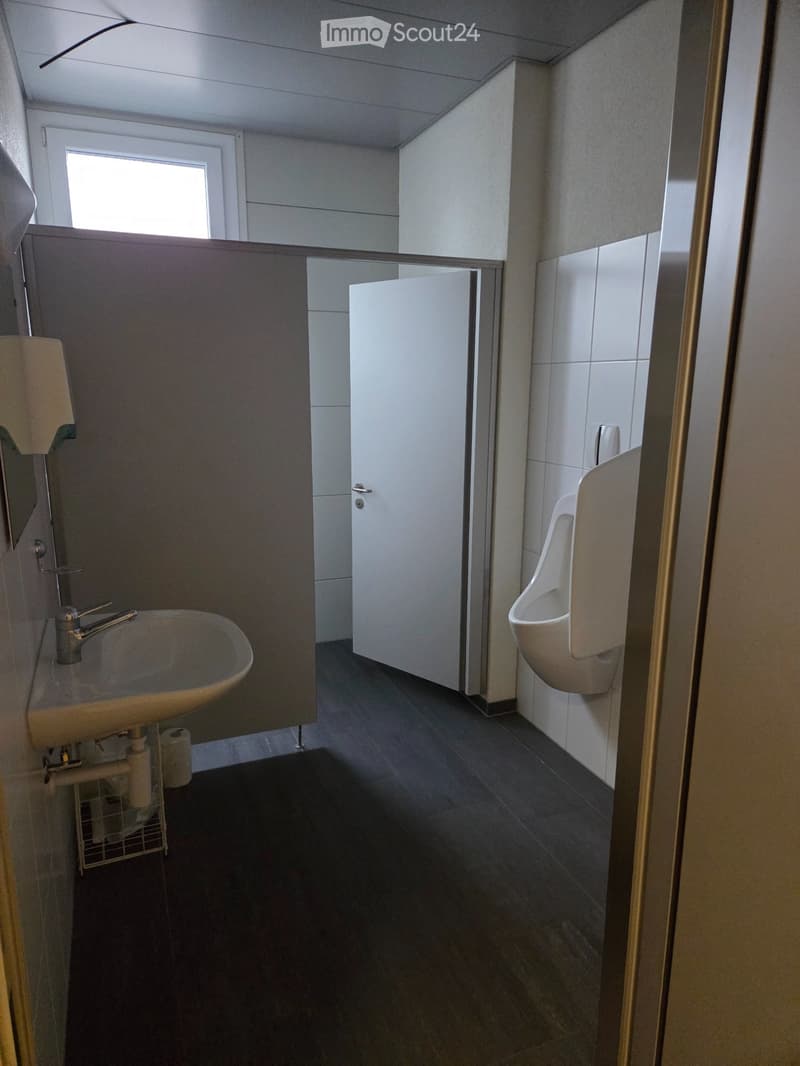 A small bathroom with a sink, urinal, and a mirror.