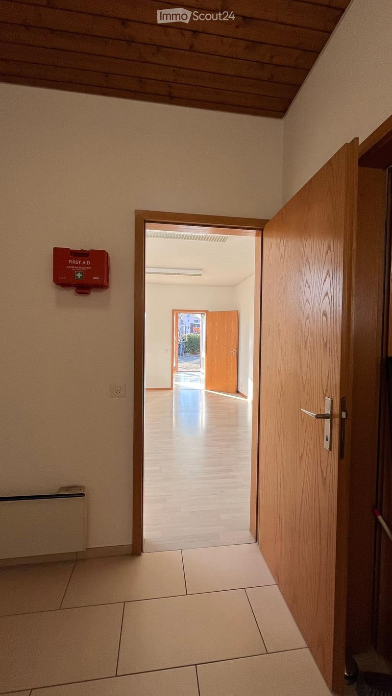 Empty room with wooden door, white walls, wooden floor, white ceiling, fire extinguisher, power outlet