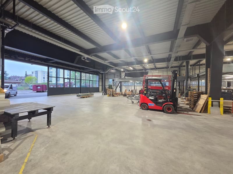 large open space, metal beams, large windows, forklift, wooden table, pallet racks, storage boxes