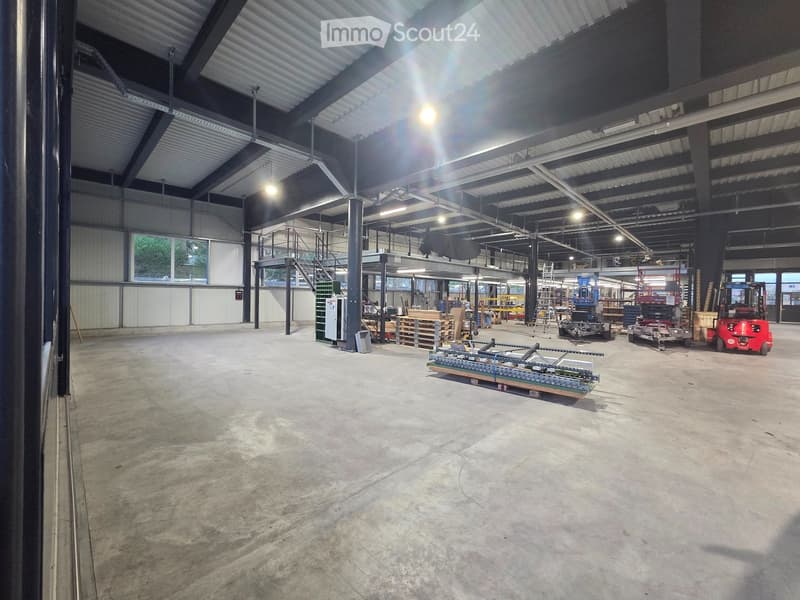 large open space, metal beams, concrete floor, forklifts, storage boxes, windows