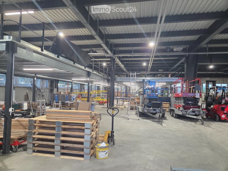 large warehouse with high ceilings, metal shelving, forklifts, pallet racks, storage boxes, buckets, and various equipment