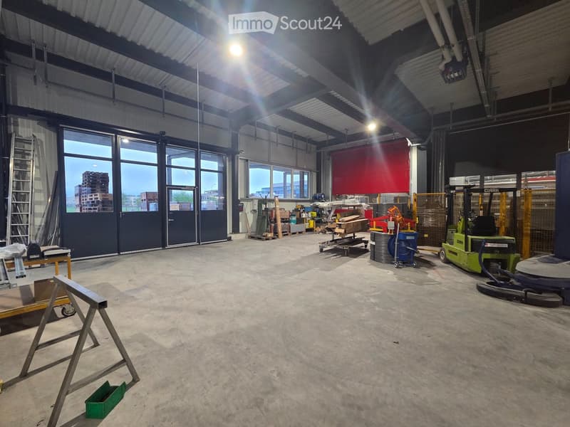 large warehouse, concrete floor, large windows, double doors, forklifts, storage boxes, ladder