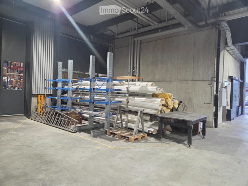 Warehouse with metal racks, wooden pallets, and various materials stored on shelves.