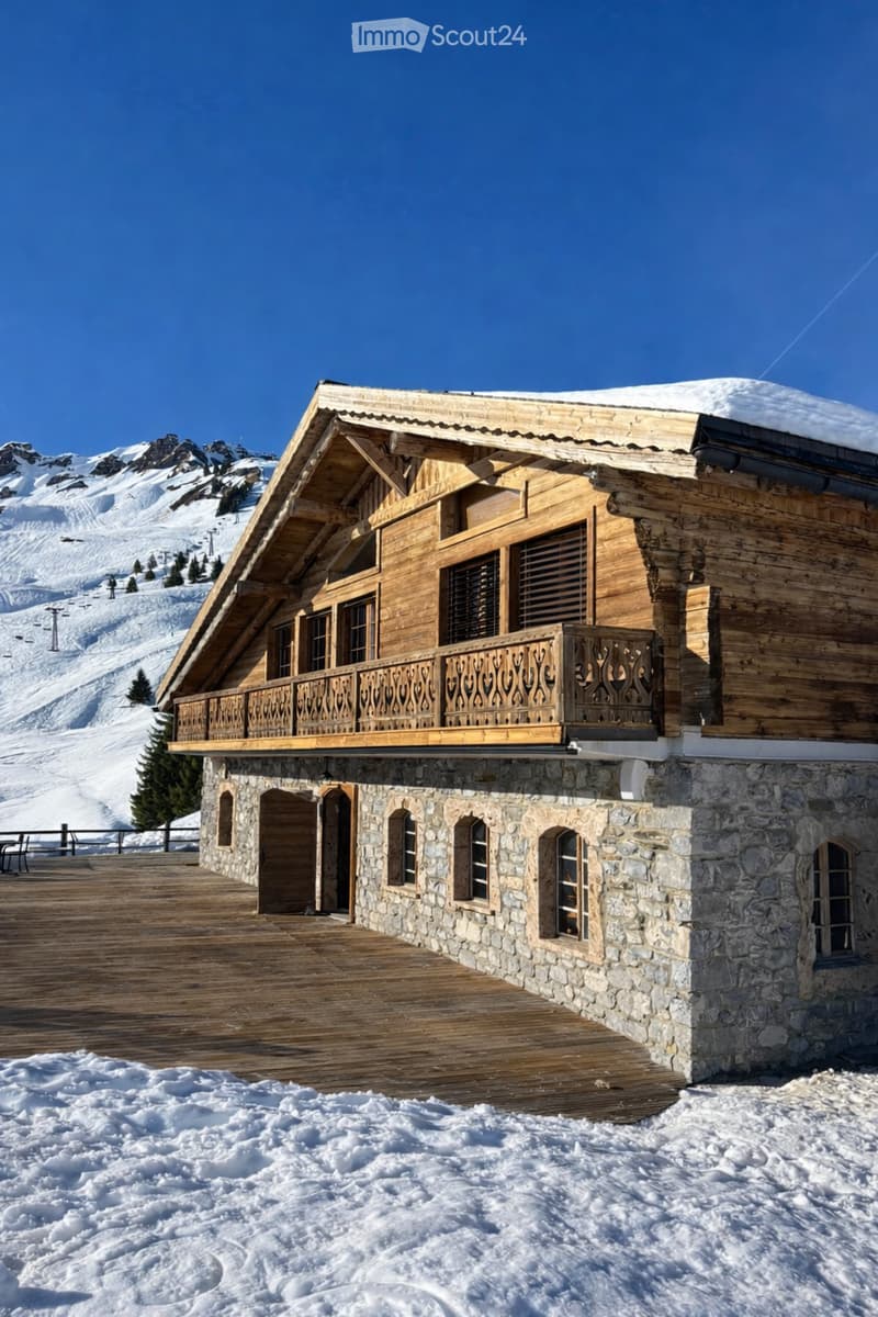 wooden chalet, stone base, balcony, wooden deck, snowy mountain in background