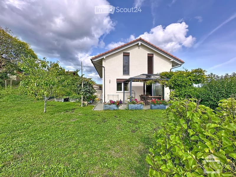 Detached house, white exterior, red roof, large windows, terrace, garden with flowers, green lawn