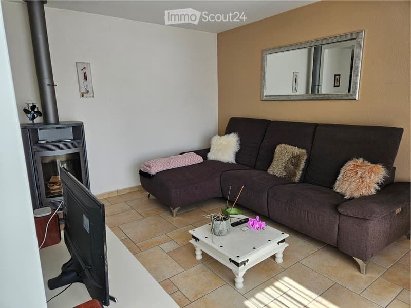Living room with fireplace, sofa, table, TV, and mirror on the wall