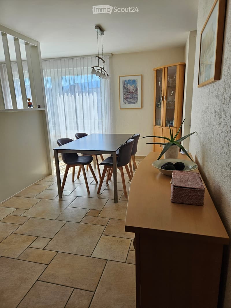 modern dining area with table and chairs, tiled floor, wooden cabinet, picture frames, white curtains, hanging lamps, potted plant