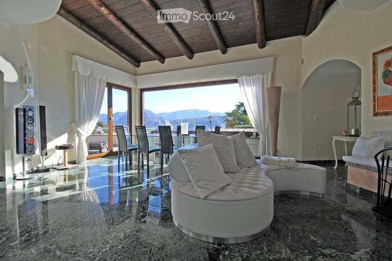 modern living room with large windows, white couch, marble floor, speakers, table, chairs, view of mountains