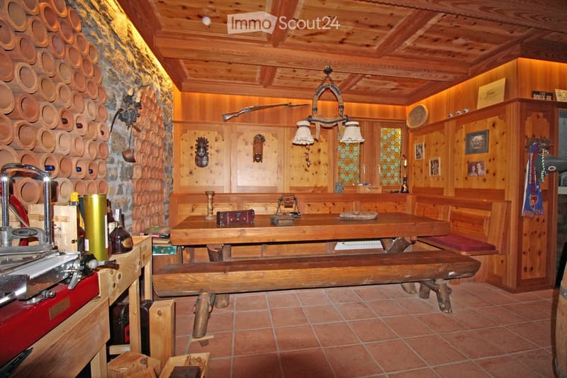 wooden table, wooden benches, wooden wall, wooden ceiling, wine rack, chandelier, wooden cabinet, picture frames, radiator