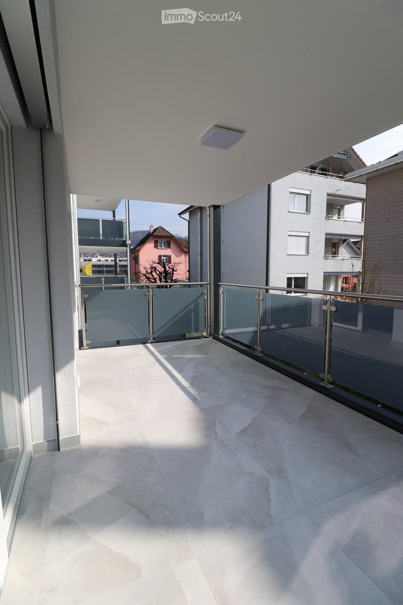 Balcony with glass railings, tiled floor, metal handrails, metal ceiling light