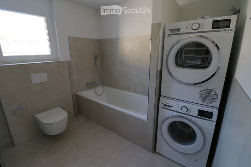 Bathroom with bathtub, toilet, washing machine, and dishwasher.