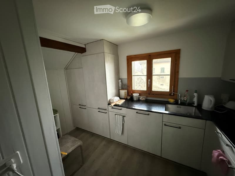 Kitchen with white cabinets, black countertops, stainless steel sink, ceiling lamp, wooden window.