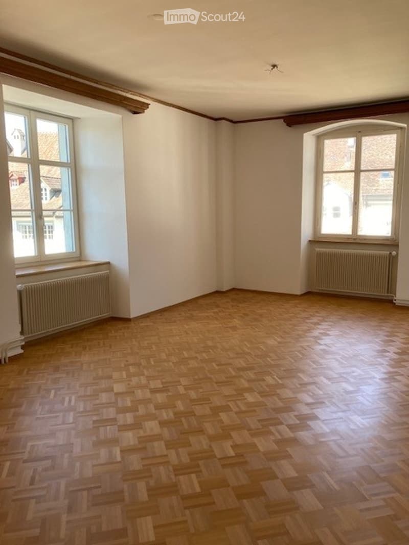 empty room, wooden parquet floor, white walls, two large windows, two radiators