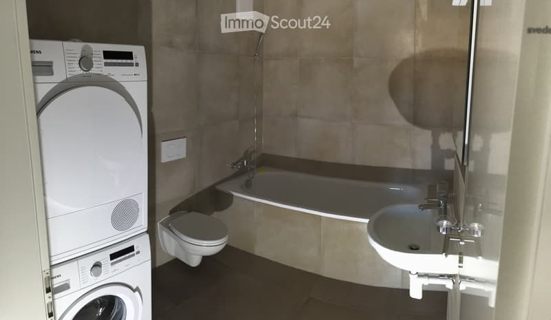 Bathroom with bathtub, sink, toilet, washing machine, and dryer