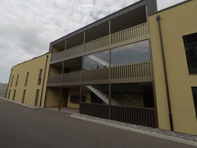 3 story building, yellow exterior, glass windows, balconies, stairs