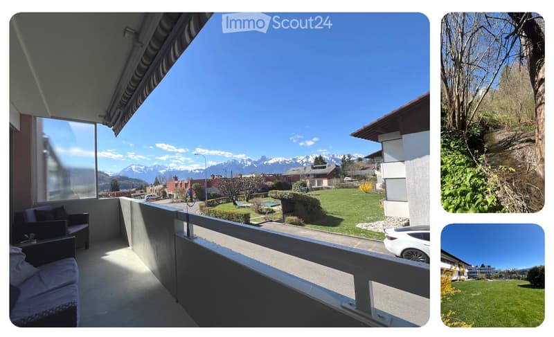 Balcony with a view of the mountains, a car parked on the street, a grassy area, and a building in the distance.