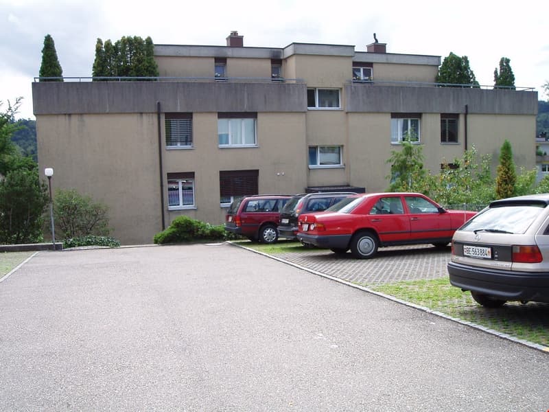 3 story building, beige exterior, multiple windows, cars parked in front