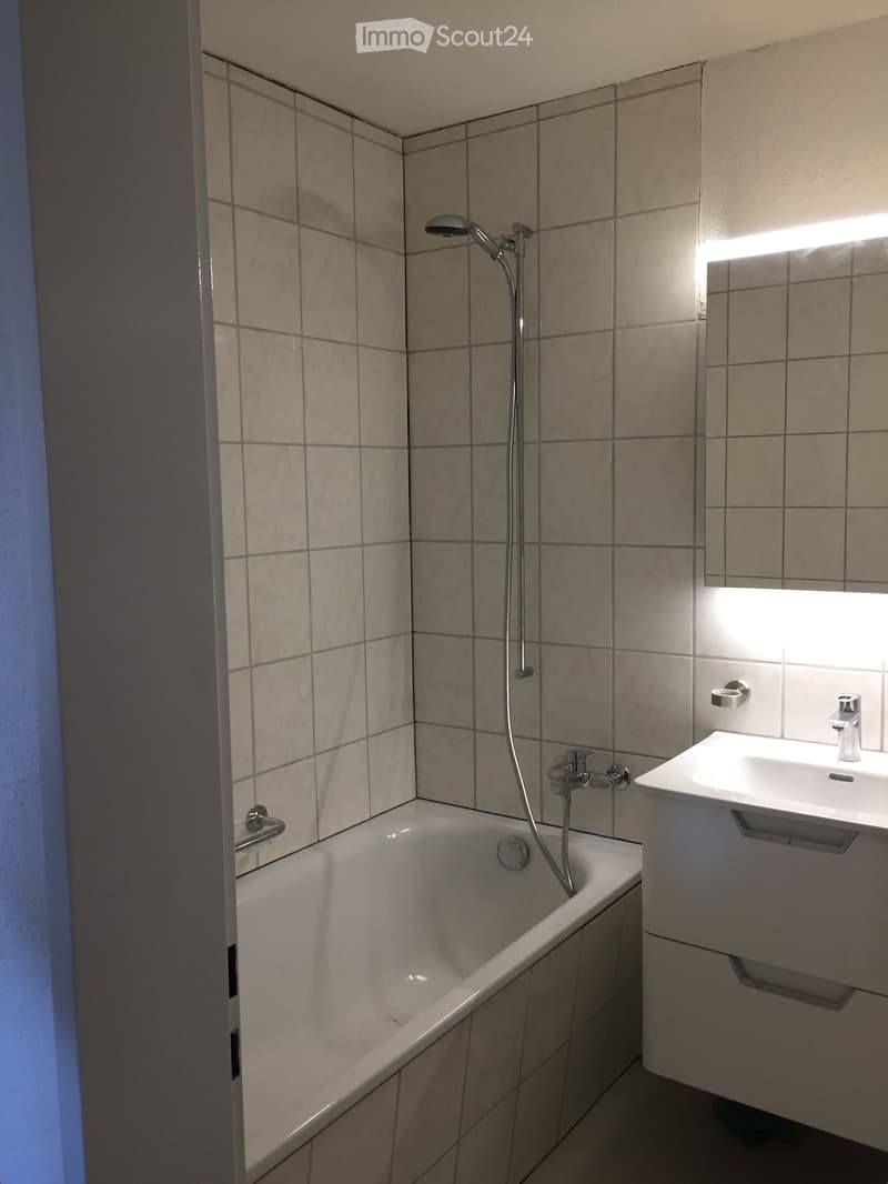 Bathroom with bathtub, shower, sink, mirror, and white tiles