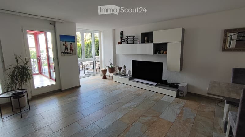 open plan living room, balcony, large windows, TV, entertainment unit, tiled floor, plants