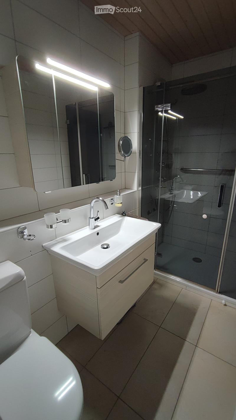 modern bathroom with white tiles, white sink, mirror, toilet, shower