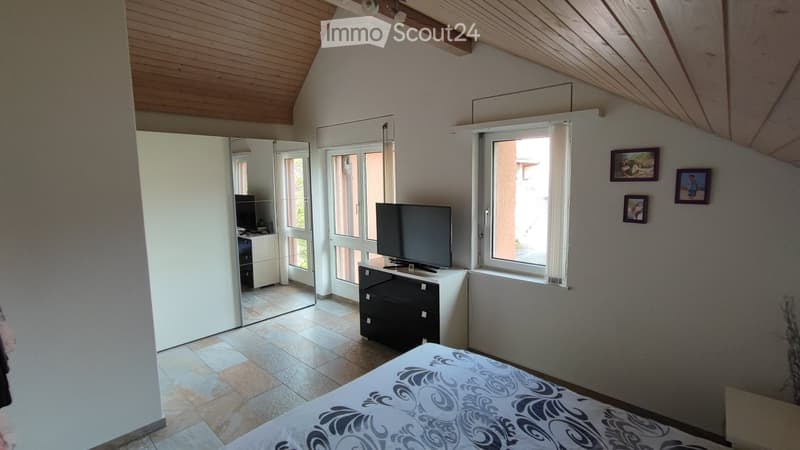 Bedroom with bed, TV, cabinet, mirror, windows, and picture frames