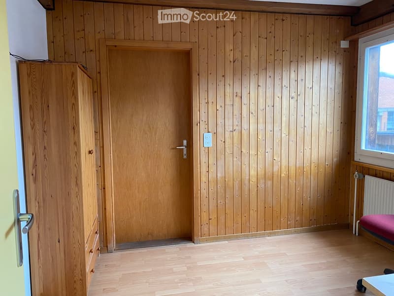 Empty room with wooden walls, wooden floor, wooden cabinet, door, window, radiator