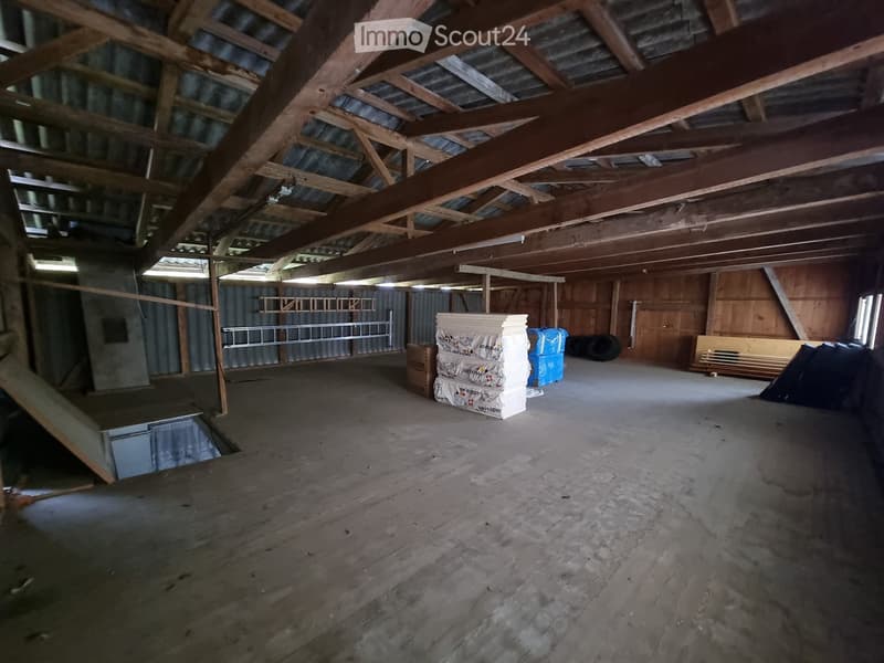 Empty room with wooden floor, wooden beams, metal walls, and a staircase