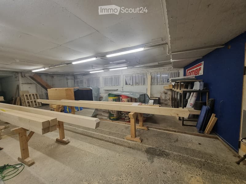 workshop with wooden workbenches, wooden planks, buckets, and storage shelves