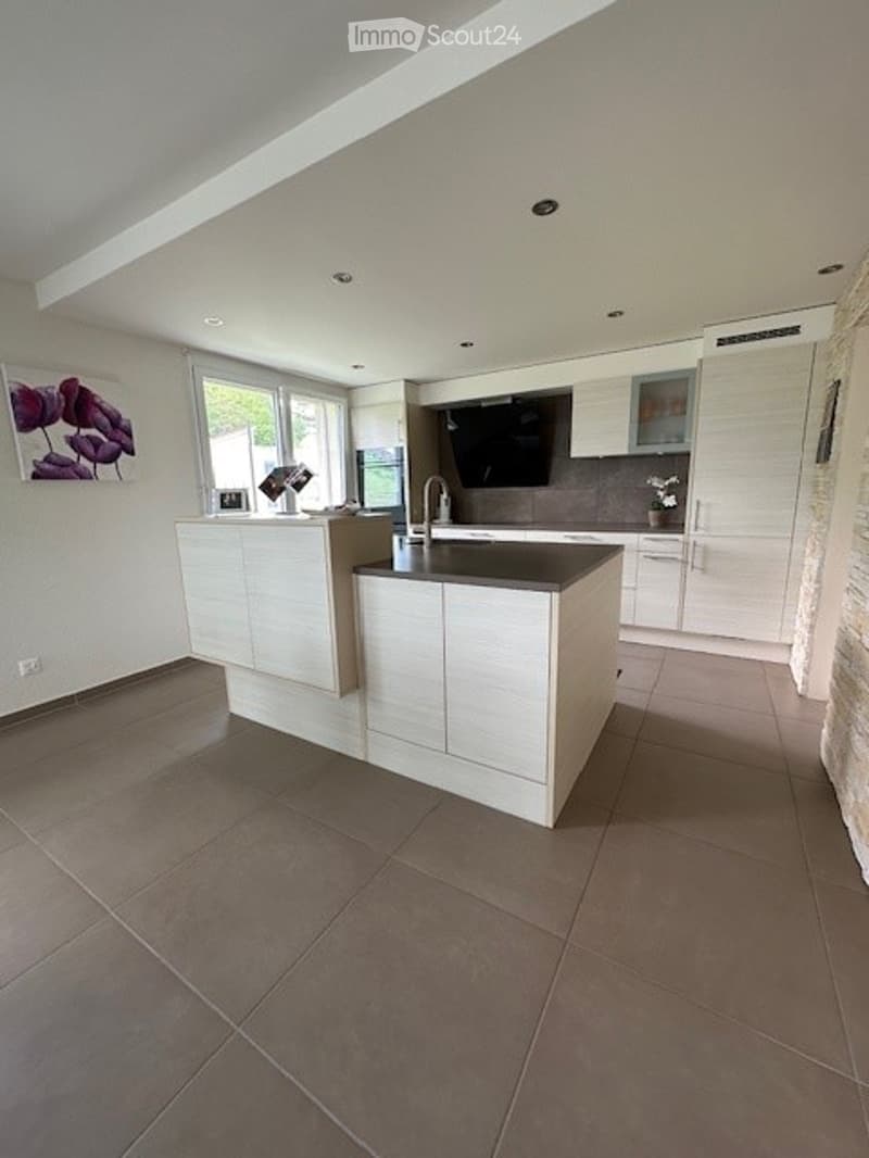 modern kitchen with island, white cabinets, granite countertops, stainless steel appliances, large window, artwork, tiled floor