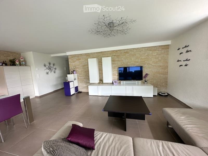 modern living room, white walls, beige tiles, white couch, purple pillows, black coffee table, white TV stand, flat screen TV, white cabinets, decorative items