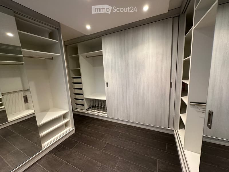 walk-in closet with white shelves, drawers, hanging rods, and a wine rack