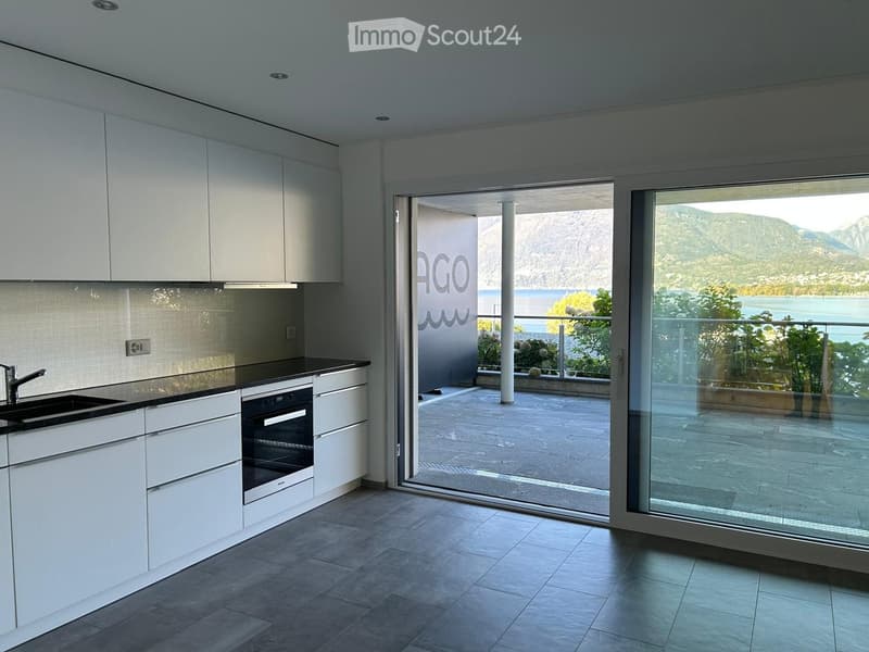 modern white kitchen, gas stove, oven, sink, white cabinets, granite countertops, glass doors leading to a balcony