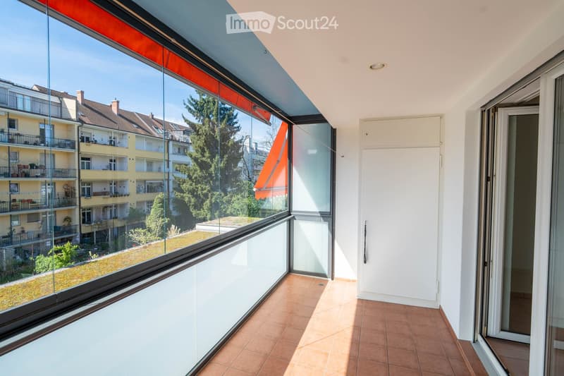 large glass windows, tiled floor, white walls, balcony with retractable awning