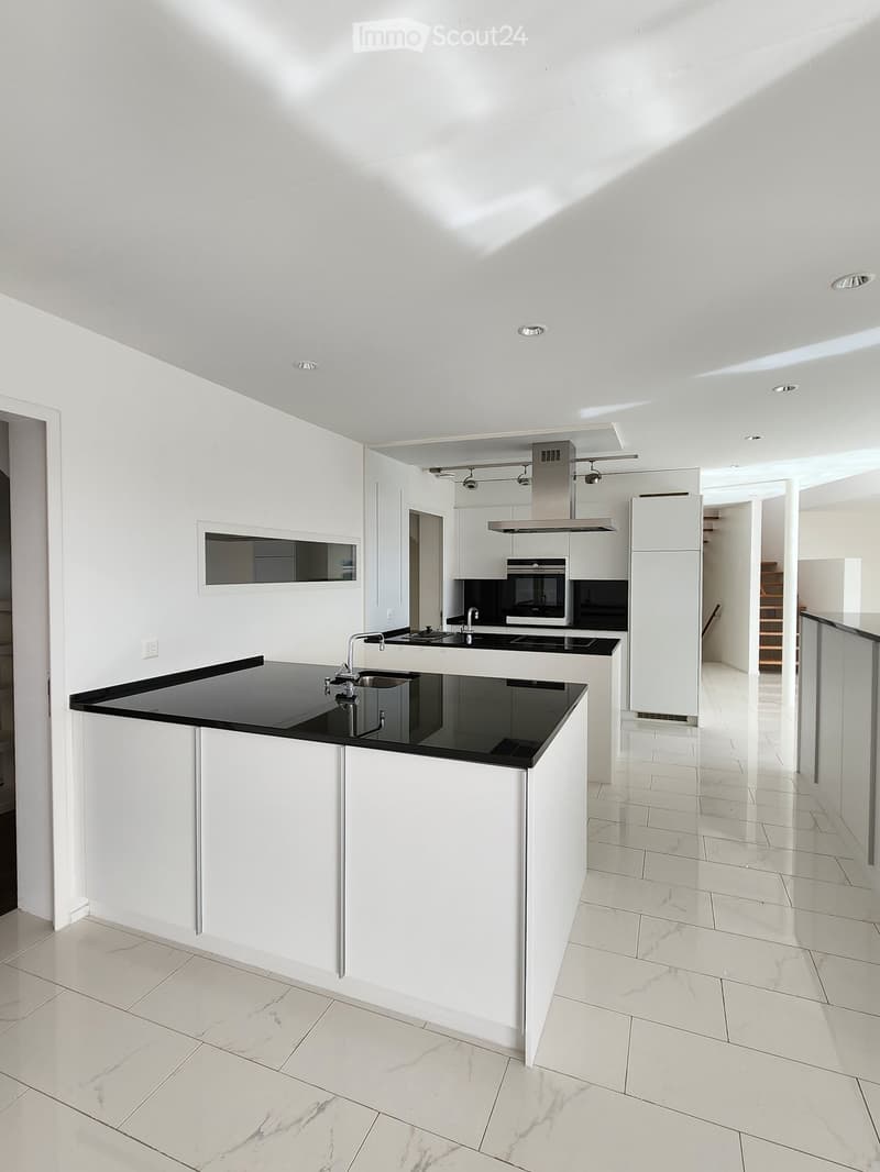 Open kitchen with modern, white cabinetry, black granite countertops, integrated appliances, and a spacious layout.