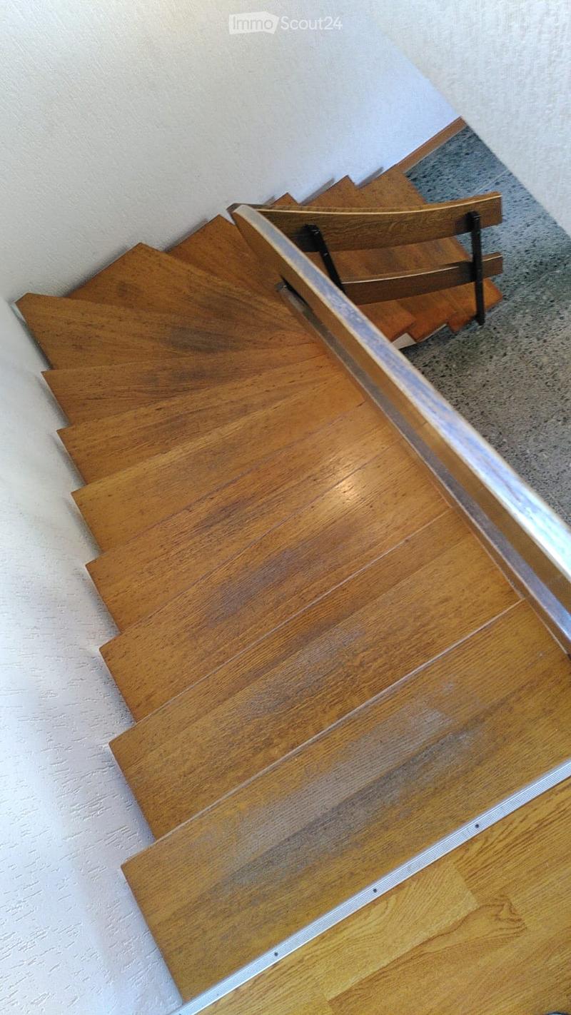 Wooden staircase with a modern design, featuring a sleek metal railing and polished wooden steps.