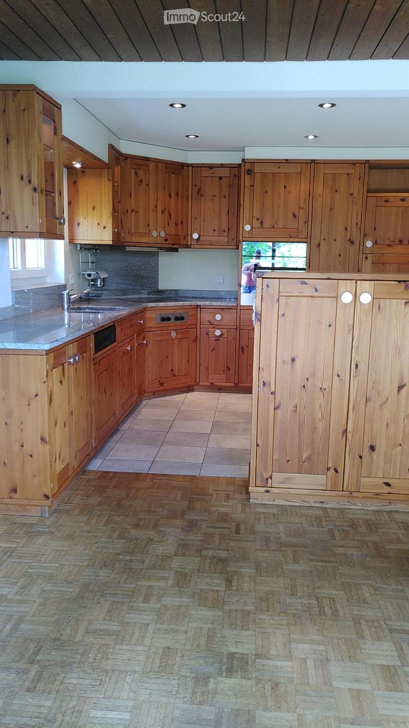Spacious kitchen with wooden cabinets, a central island, and a tiled backsplash. Features a sink with a modern faucet and recessed ceiling lighting.