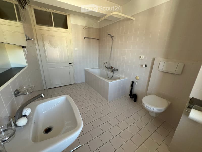 Bathroom with white tiles, bathtub, toilet, sink, and shower