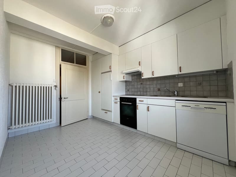 modern kitchen with white cabinets, white tiled floor, black oven, dishwasher, sink, faucet, white radiator