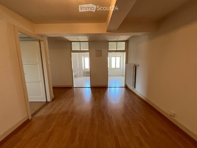 Empty hallway with wooden floors, white walls, and three doors leading to different rooms.
