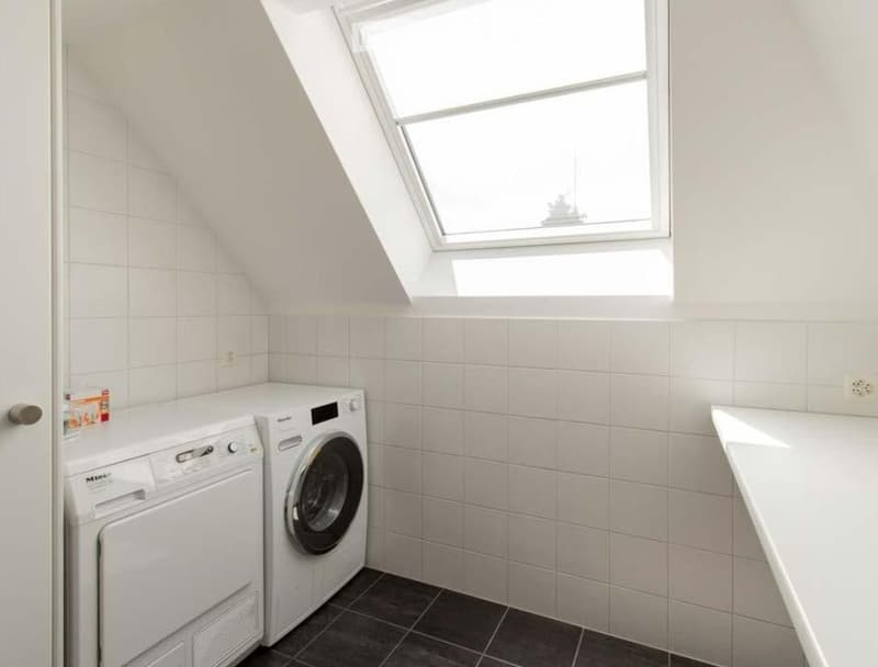 A small laundry room with a washing machine, a dryer, and a window.