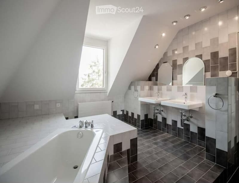 Bathroom with bathtub, two sinks, and a window