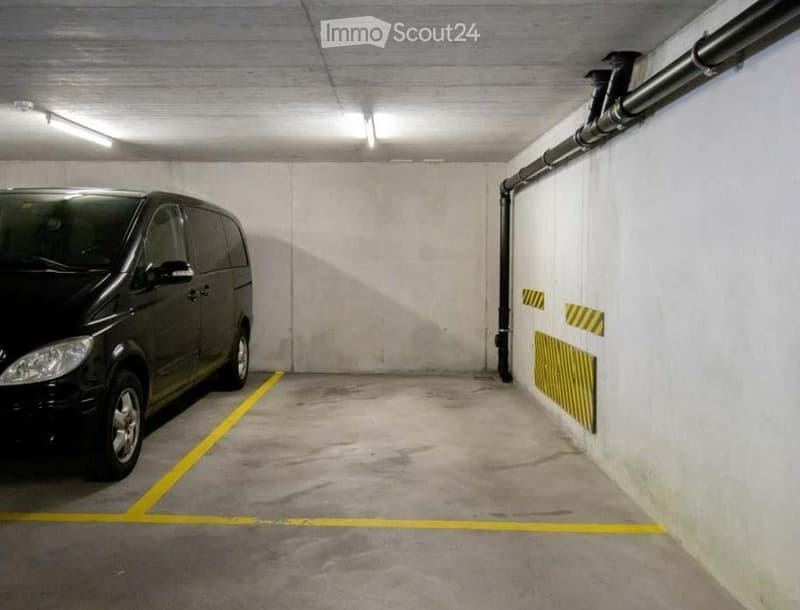 underground parking space, yellow lines, white walls, black van parked