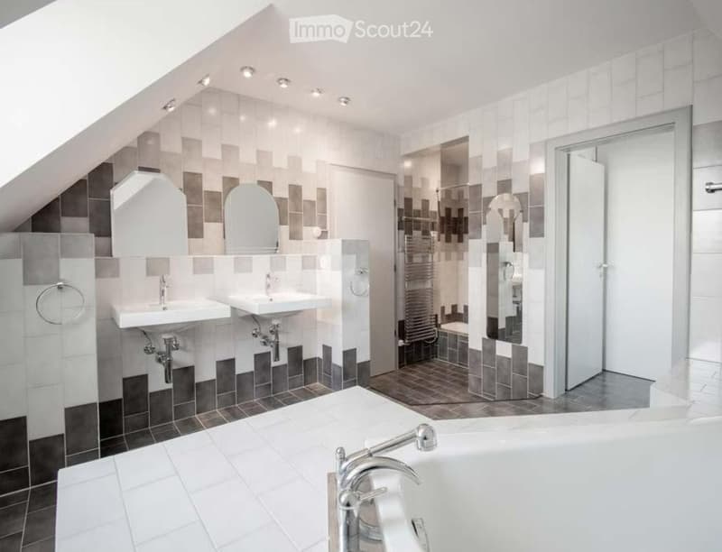 modern bathroom with white bathtub, two sinks, shower, and tiled walls