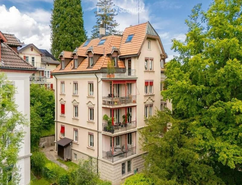 3 story house, beige walls, brown roof, multiple balconies, surrounded by trees